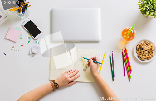 Image of woman hands drawing in notebook at home office