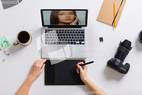 Image of woman with camera working on laptop at table