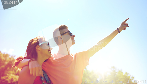 Image of happy couple pointing finger at summer park