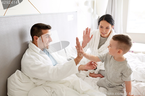 Image of happy family in bed at home or hotel room