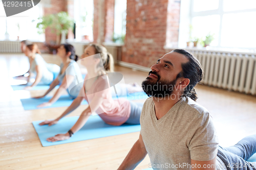 Image of group of people doing yoga cobra pose at studio