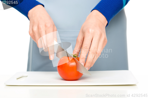 Image of Cook is chopping red tomato