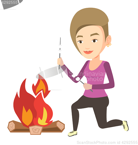 Image of Woman roasting marshmallow over campfire.