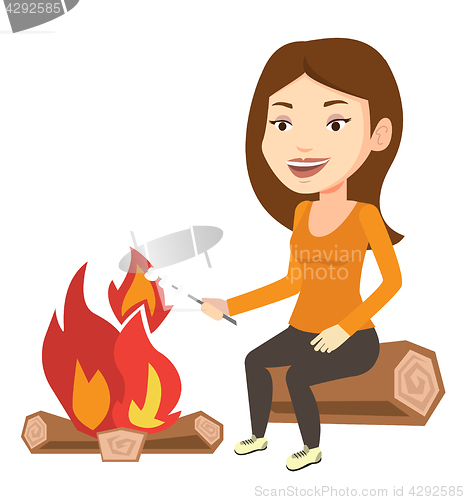 Image of Woman roasting marshmallow over campfire.