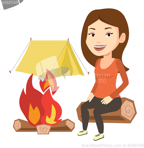 Image of Woman sitting on log near campfire in the camping.