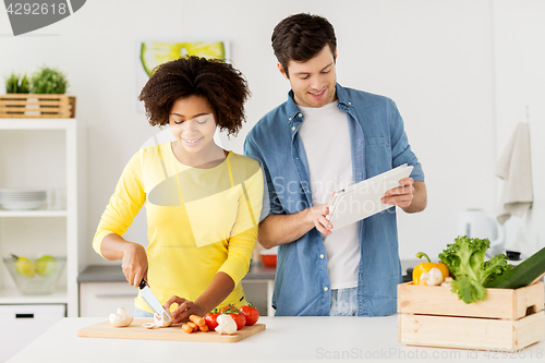 Image of happy couple with tablet pc cooking food at home