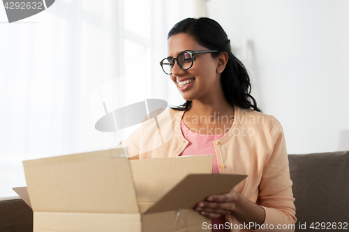 Image of happy young indian woman with parcel box at home