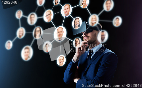 Image of businessman in virtual reality headset over black