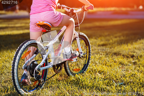 Image of Little girl on a bicycle in summer park