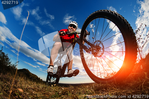 Image of cyclist riding mountain bike on rocky trail at sunrise