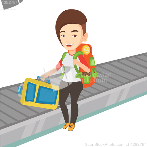 Image of Woman picking up suitcase on luggage conveyor belt