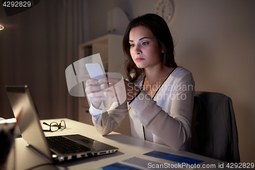 Image of businesswoman with smartphone and laptop at office