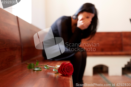 Image of crying woman with red rose at funeral in church