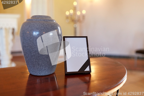 Image of photo frame with mourning ribbon and cremation urn