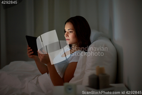 Image of young woman with tablet pc in bed at home bedroom