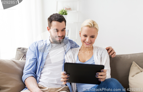 Image of smiling happy couple with tablet pc at home