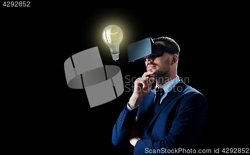 Image of businessman in virtual reality headset over black