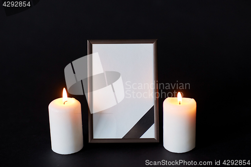 Image of black ribbon on photo frame and candles at funeral