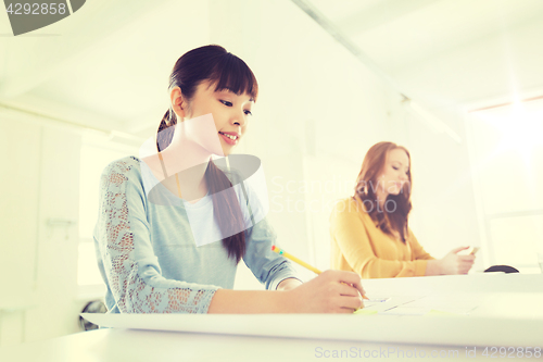 Image of architect woman with blueprint writing at office