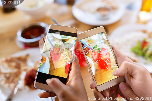 Image of hands with drinks on smartphones at restaurant