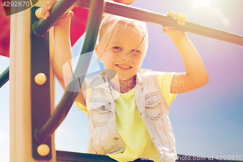 Image of happy little girl climbing on children playground