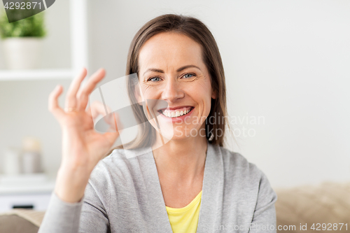 Image of happy smiling woman showing ok hand sign at home
