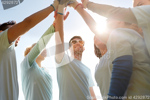 Image of group of volunteers making high five outdoors