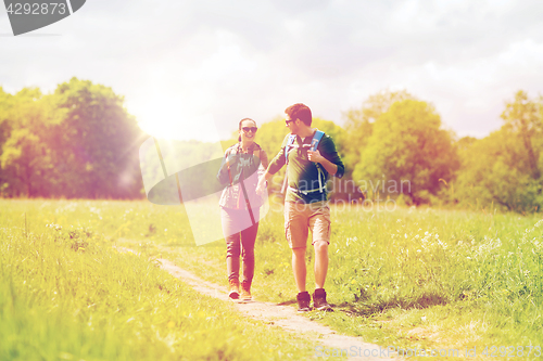 Image of happy couple with backpacks hiking outdoors