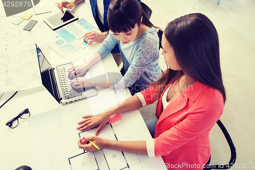 Image of creative team with laptop and blueprint at office