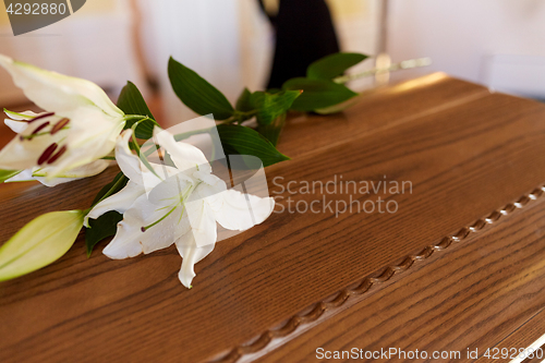 Image of lily flower on wooden coffin at funeral in church