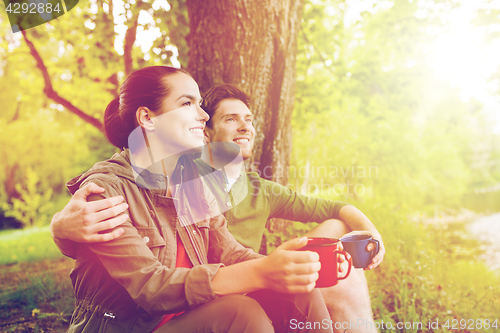 Image of happy couple with cups drinking in nature