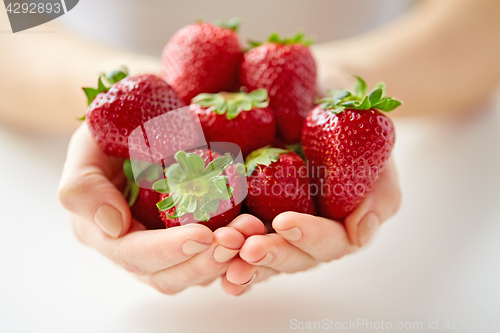 Image of close up of young woman hands holding strawberries