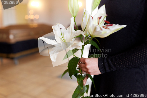 Image of close up of woman with lily flowers at funeral