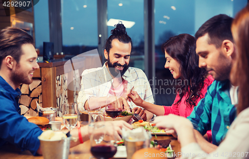 Image of friends eating and tasting food at restaurant