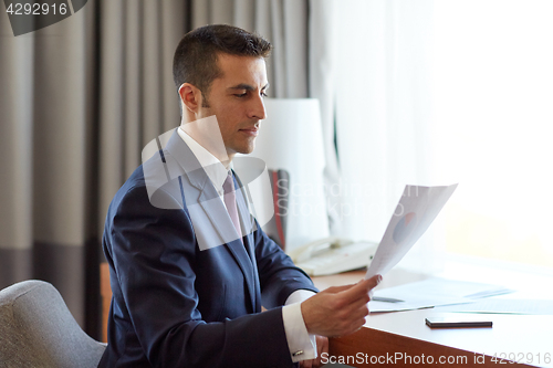 Image of businessman with papers working at hotel room