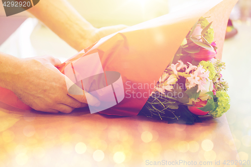 Image of florist wrapping flowers in paper at flower shop