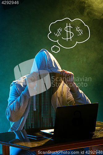 Image of Hooded computer hacker stealing information with laptop