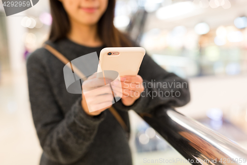 Image of Woman working on cellphone in shopping mall