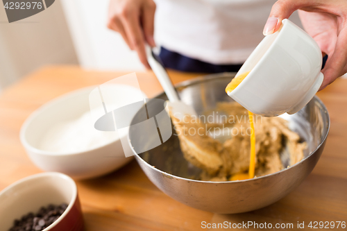 Image of Adding egg inside the dough for making cookies