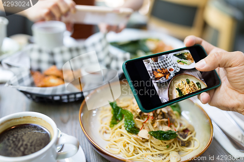 Image of Friends taking photo on cellphone in restaurant