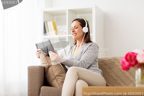 Image of happy woman with tablet pc and headphones at home