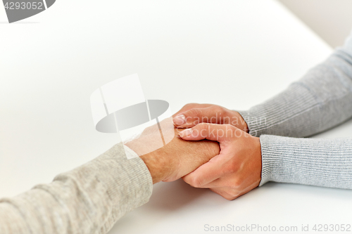 Image of close up of old man and young woman holding hands