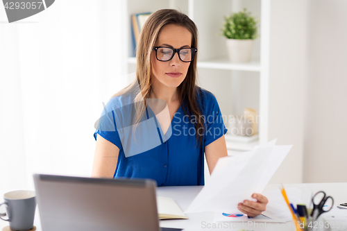 Image of happy woman with papers and laptop at office