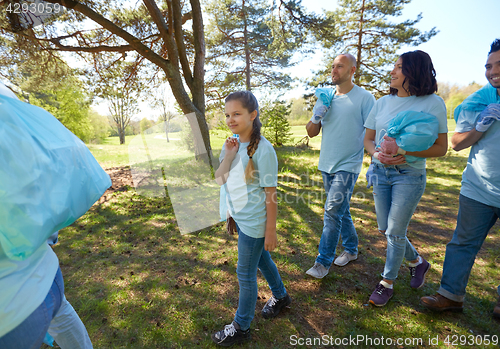 Image of volunteers with garbage bags walking outdoors