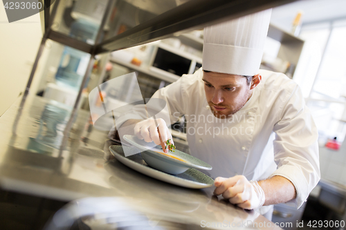 Image of happy male chef cooking food at restaurant kitchen