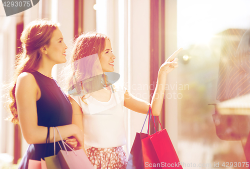 Image of happy women with shopping bags at shop window