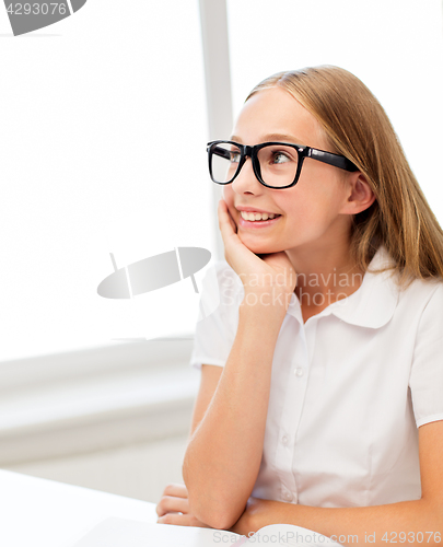 Image of happy student girl in glasses with book at school