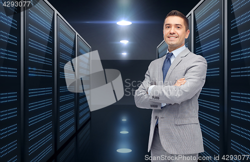 Image of smiling businessman over server room background