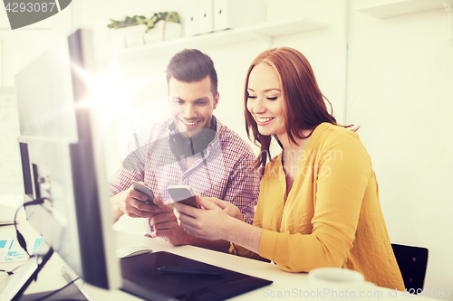 Image of happy creative team with smartphones at office