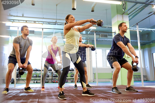 Image of group of people with kettlebells exercising in gym